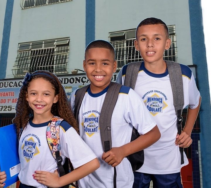 Alunos sorridentes com o uniforme do Mendonça Goulart em frente à escola